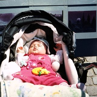 Baby sleeping in a stroller, displayed in front of photos.