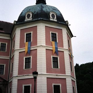 Pink and white castle section with flags and a lamp.