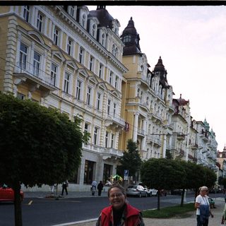 Woman with walking sticks stands in front of a building.
