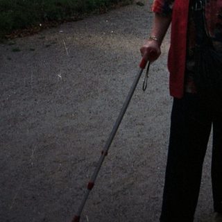 Woman with walking sticks stands in front of a building.