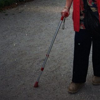 Woman with crutches stands on a street near buildings.