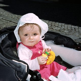 Baby in stroller holding a toy duck.