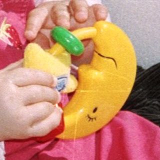 Baby in stroller holding a toy duck.
