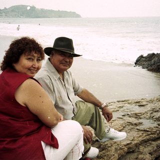 Couple sitting on rocks, enjoying a beach day.