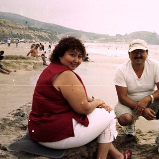Couple poses on rocks at a crowded beach.