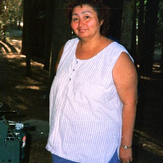 Here's a brief summary of the image: Woman stands near camping gear in a wooded area.