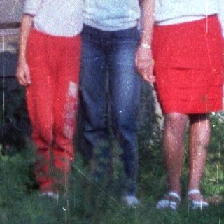 Three children standing in front of a building.