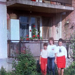 Three children standing in front of a building.