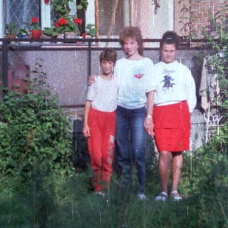 Three children standing in front of a building.