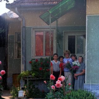 Group of children standing outside a house with flowers.