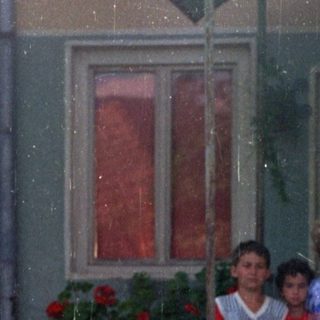 Group of children standing outside a house with flowers.