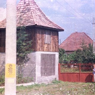 Red fence, wooden building, and a person in a rural setting.