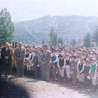 Group of boys in uniforms stand outdoors with men.