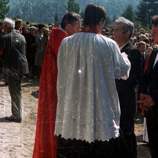 People gather outdoors, possibly at a religious ceremony.