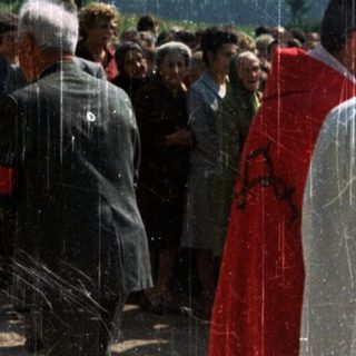 People gather outdoors, possibly at a religious ceremony.