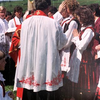 Outdoor religious ceremony with traditional costumes and attendees.