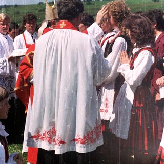 Outdoor religious ceremony with traditional costumes and attendees.