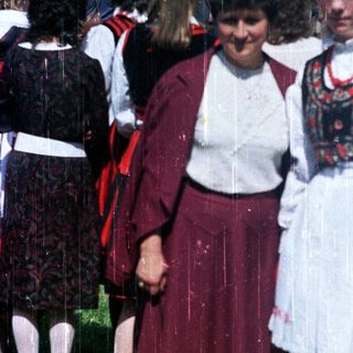 Two women in traditional folk dress stand in a crowd.