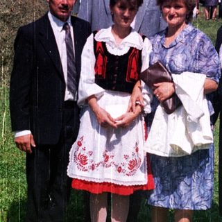 Family posing outdoors amidst a crowd on a grassy field.