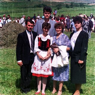 Family posing outdoors amidst a crowd on a grassy field.