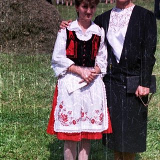 Two women stand in a field during a gathering.