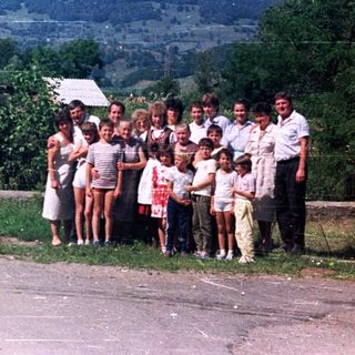 Group portrait outdoors, featuring a family and scenic hillside backdrop.