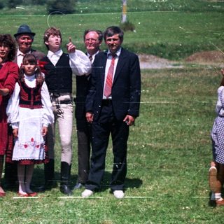 Family in traditional dress poses for a photo outdoors.