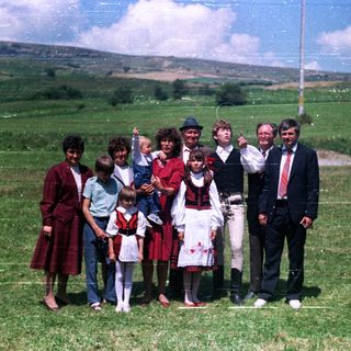 Family in traditional dress poses for a photo outdoors.