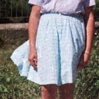 Girl stands on a road with a weeping willow tree.