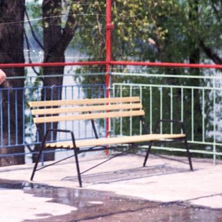 Here's a brief summary of the image: Four men and a woman stand near a railing with a bench.