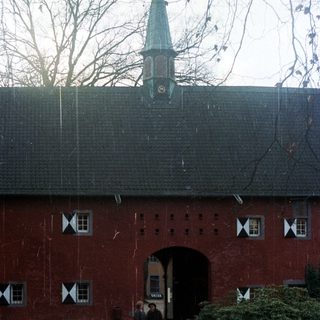 People walk toward a red brick building with a tower.