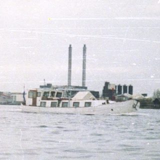 Boat on water with industrial landscape in the background.