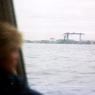 Boat on water with industrial landscape in the background.