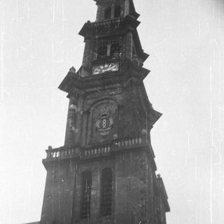 Here's a brief summary of the image: Tall, old stone tower with a clock and spire.