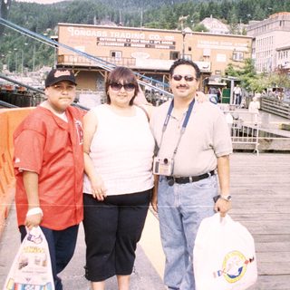 Three people pose on a pier with a waterfront view.