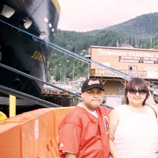 Three people pose on a pier with a waterfront view.