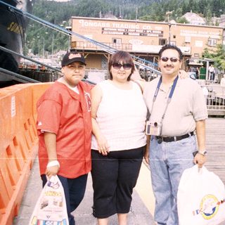 Three people pose on a pier with a waterfront view.