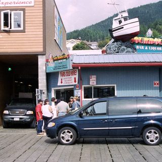 Storefront with a vehicle, people, and a boat display.