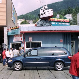 Storefront with a vehicle, people, and a boat display.
