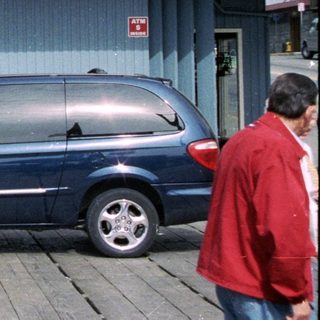 Storefront with a vehicle, people, and a boat display.