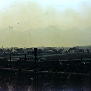 Train tracks stretch toward a town and distant mountains.