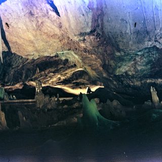 Here's a brief summary of the image: Interior view of a dark cave with rock formations.