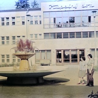 Fountain and building exterior with people standing nearby.