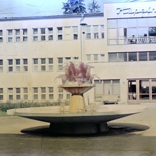 Fountain and building exterior with people standing nearby.