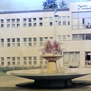 Fountain and building exterior with people standing nearby.