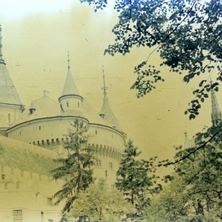 A castle with tall spires and a stone wall.