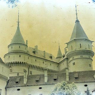 An aged photograph depicts a castle with pointed towers.