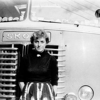 Woman poses in front of a vintage Škoda bus.