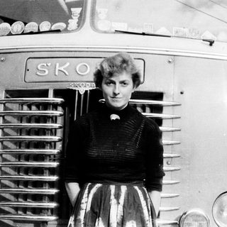 Woman poses in front of a vintage Škoda bus.
