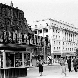 Wartime destruction juxtaposed with a rebuilt, bustling city street.